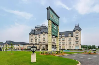 a large building with a sign in front of it at Quality Suites in Drummondville