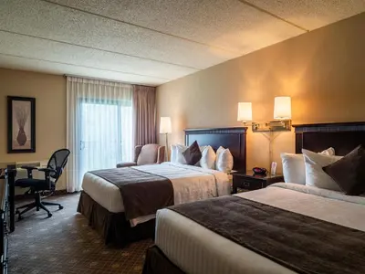 a hotel room with two beds and a desk at Le President Sherbrooke in Sherbrooke