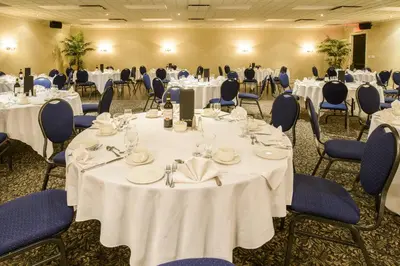 a banquet room with white tables and blue chairs at Le President Sherbrooke in Sherbrooke