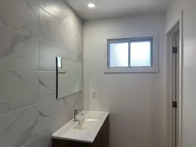 a white bathroom with a sink and a window at Motel Chez Nous in Laval