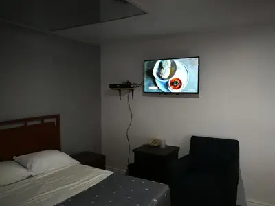 a bedroom with a bed and a tv on the wall at Motel Chez Nous in Laval