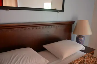 a bed with a wooden headboard and a lamp and a mirror at Motel Chez Nous in Laval
