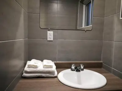 a bathroom with a sink and a mirror and towels at Motel Chez Nous in Laval