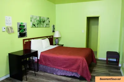 a bedroom with a bed with a red blanket and a desk at Hotel Casa Bella in Montréal