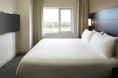 a large white bed in a hotel room with a window at Residence Inn by Marriott Montreal Airport in Dorval