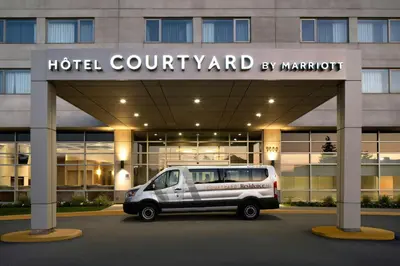 a van parked in front of a hotel courtyard by marriott at Courtyard by Marriott Montreal Airport in Dorval