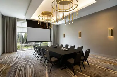 a conference room with a black table and chairs and a projection screen at Courtyard by Marriott Montreal Airport in Dorval