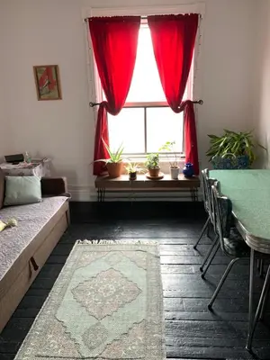 a living room with a window with red curtains at Pensione Popolo in Montréal