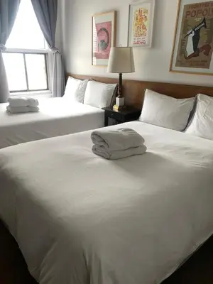 two white beds in a bedroom with a window at Pensione Popolo in Montréal