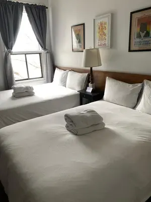 a bedroom with two beds with white sheets and a window at Pensione Popolo in Montréal