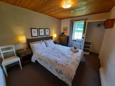 a bedroom with a bed and a chair and a window at Auberge Schweizer in Sutton