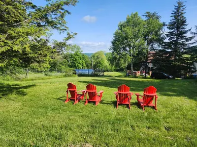a group of red chairs sitting in the grass at Auberge Schweizer in Sutton