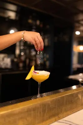 a person pouring a drink into a martini glass at Holiday Inn St-Jean-sur-Richelieu Congrès by IHG in Saint-Jean-sur-Richelieu