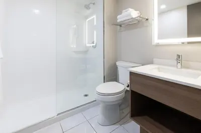a white bathroom with a toilet and a sink at Holiday Inn St-Jean-sur-Richelieu Congrès by IHG in Saint-Jean-sur-Richelieu