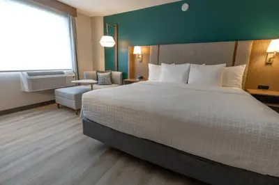 a hotel room with a large bed and a chair at Holiday Inn St-Jean-sur-Richelieu Congrès by IHG in Saint-Jean-sur-Richelieu