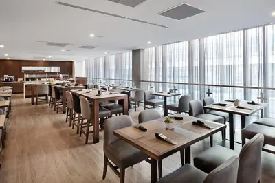 a restaurant with wooden tables and chairs and windows at Hôtel AC Montréal Centre-ville in Montréal