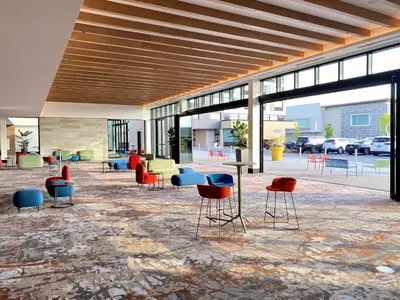 a lobby with colorful chairs and tables and windows at Sheraton Laval Hotel in Laval