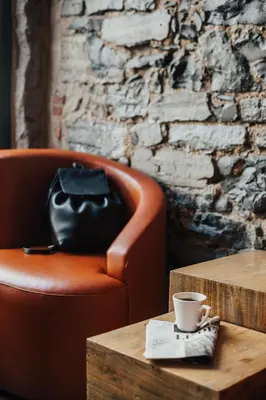 a leather chair and a table with a coffee cup at Le Petit Hôtel Vieux-Montréal - Saint-Paul by Gray Collection in Montréal