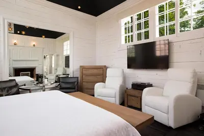 a bedroom with a bed and two chairs and a tv at Hôtel Le Rivage in Rosemère