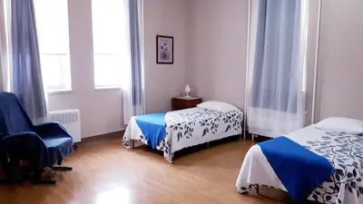 a room with two beds and a chair in it at MHotel Domaine l'Envolée- Maison Fleurie in Victoriaville