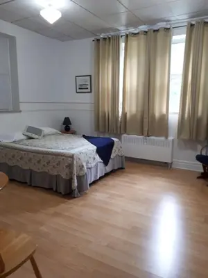 a bedroom with a bed in a room with wooden floors at MHotel Domaine l'Envolée- Maison Fleurie in Victoriaville