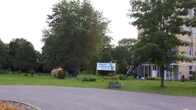a building with a sign on the side of a street at MHotel Domaine l'Envolée- Maison Fleurie in Victoriaville