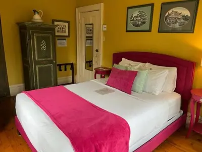 a bedroom with a large bed with a pink blanket at La Belle Victorienne in Magog-Orford