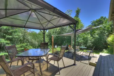 a patio with a table and chairs and umbrellas at La Belle Victorienne in Magog-Orford