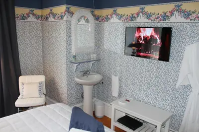 a bathroom with a bed and a sink and a mirror at La Belle Victorienne in Magog-Orford
