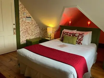 a bedroom with a large bed with a red wall at La Belle Victorienne in Magog-Orford