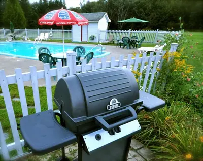 a grill sitting on a bench next to a fence at Motel de la Pente Douce in Magog-Orford