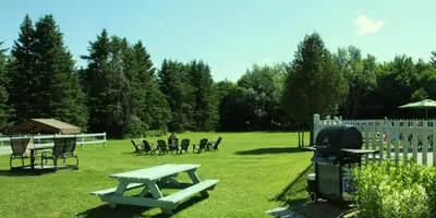 a picnic table and a grill in a yard at Motel de la Pente Douce in Magog-Orford