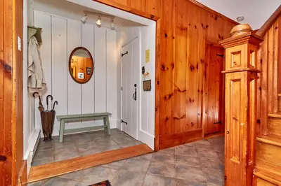 a hallway with a green table in a room with wooden walls at Auberge de la Tour et Spa in Magog-Orford