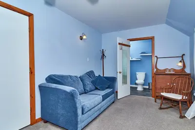 a blue living room with a blue couch and a toilet at Auberge de la Tour et Spa in Magog-Orford