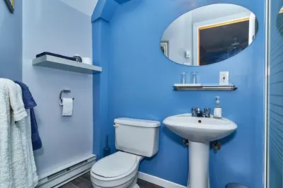 a blue bathroom with a toilet and a sink at Auberge de la Tour et Spa in Magog-Orford