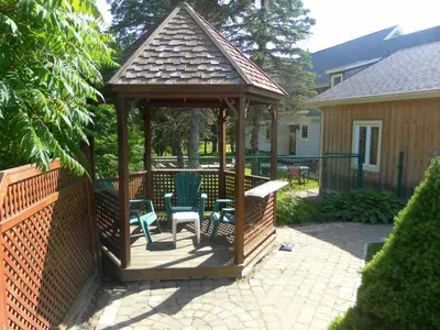 a wooden gazebo with chairs and a bench at Auberge de la Tour et Spa in Magog-Orford