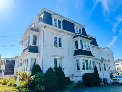 a white house with a blue roof at Le Chateau du Lac in Magog-Orford