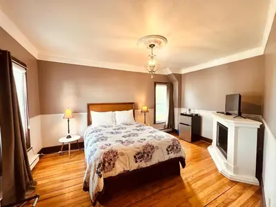 a bedroom with a bed and a television in it at Le Chateau du Lac in Magog-Orford