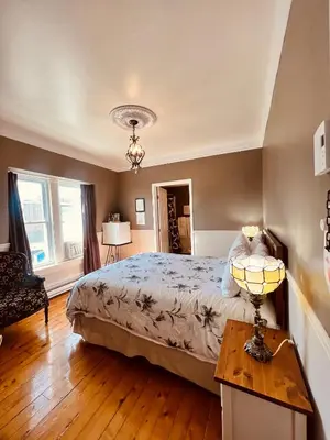 a bedroom with a bed and a table with a lamp at Le Chateau du Lac in Magog-Orford
