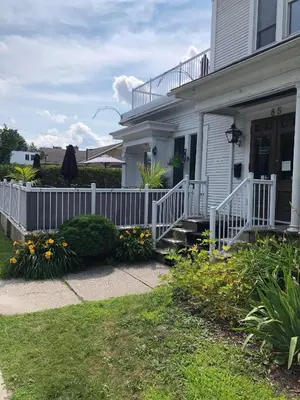 a white house with a white fence and flowers at Le Chateau du Lac in Magog-Orford