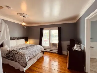 a bedroom with a bed and a window at Le Chateau du Lac in Magog-Orford