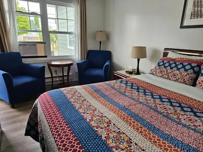 a bedroom with a bed and two blue chairs at Motel de l'Outlet in Magog-Orford