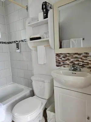 a white bathroom with a toilet and a sink at Motel de l'Outlet in Magog-Orford