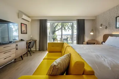 a bedroom with a large bed and a yellow couch at Hôtel Versō in Magog-Orford