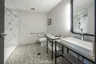 a bathroom with a sink and a toilet and a mirror at Hôtel Versō in Magog-Orford