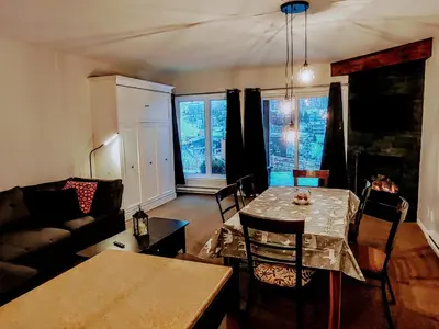 a living room with a table and a couch at Au pied des pentes in Bromont