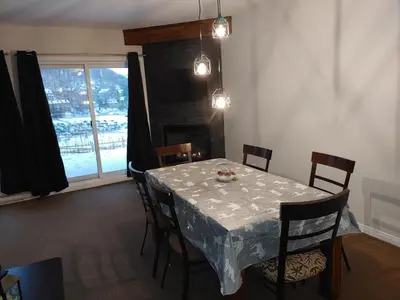 a dining room with a table and chairs and a window at Au pied des pentes in Bromont