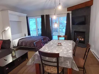 a room with a table and a bed and a fireplace at Au pied des pentes in Bromont