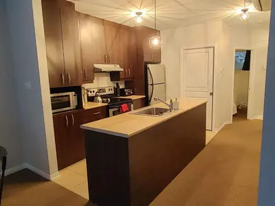 a kitchen with wooden cabinets and a sink and a stove at Au pied des pentes in Bromont