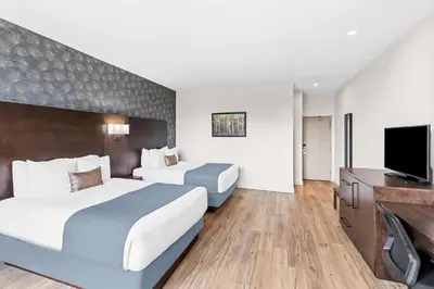 a hotel room with two beds and a flat screen tv at Best Western Plus Montreal East in Montréal